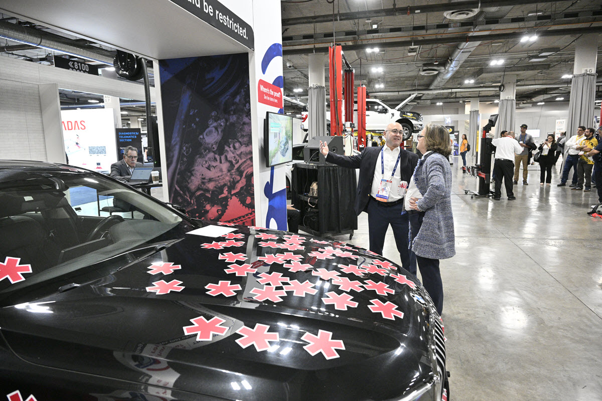 An exhibitor walks an attendee through a vehicle demo on the show floor